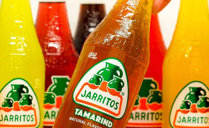 A bottle of Jarritos Mexican soft drink, known for its vibrant fruit flavors like lime, mango, and tamarind, offering a refreshing and fizzy experience.