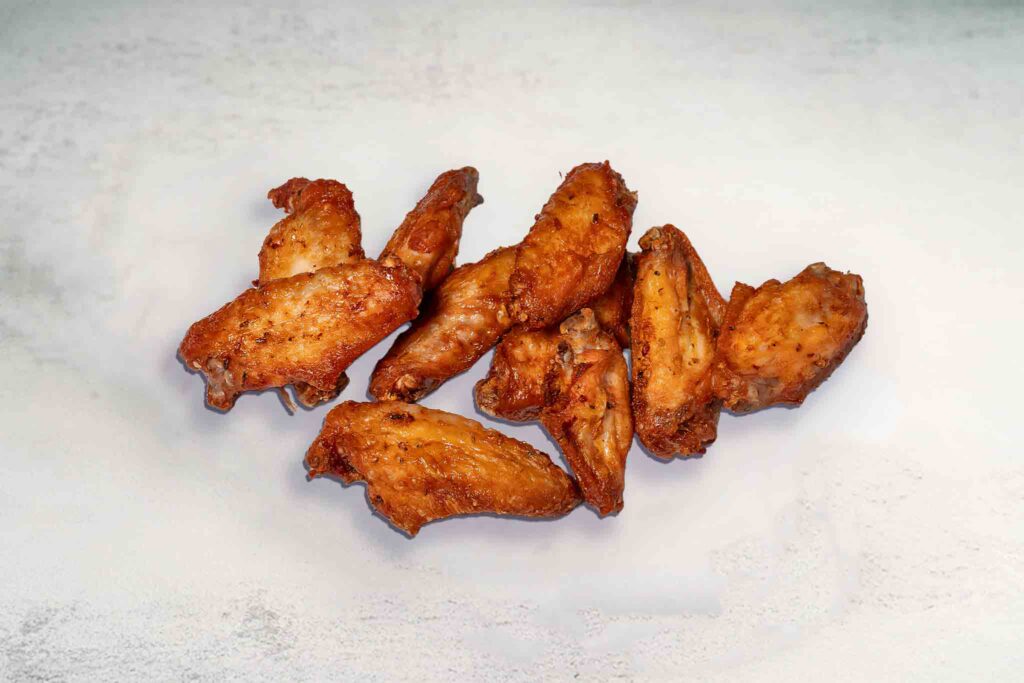 Ten crispy fried chicken wings arranged on a plate, with a golden-brown exterior and juicy interior.