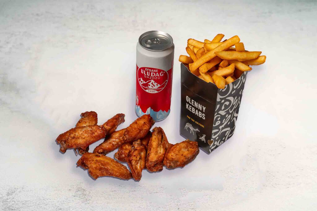 A meal featuring 10 crispy fried chicken wings, regular seasoned chips, and a can of soft drink on a plate.