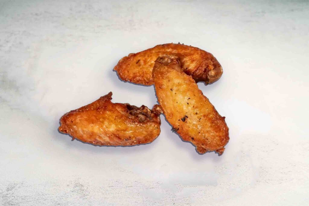 Three crispy fried chicken wings served on a plate, golden and delicious.