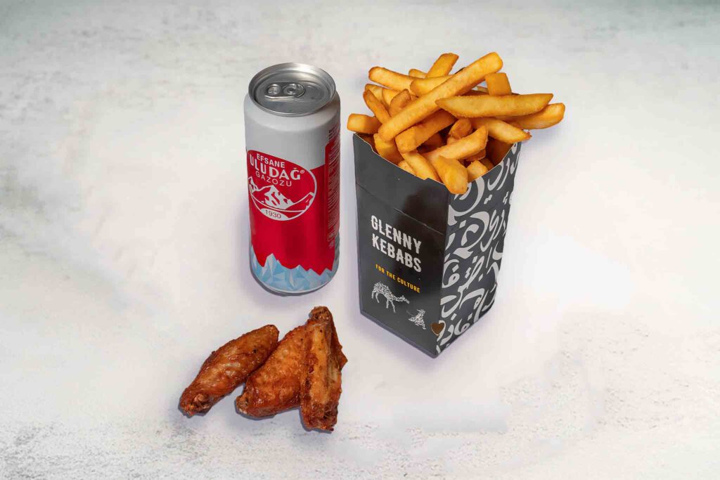 Three crispy fried chicken wings, seasoned chips, and a soft drink can served on a plate.