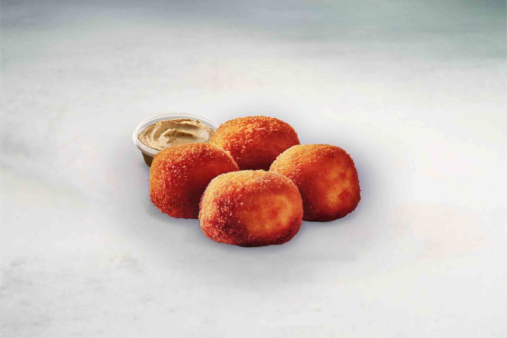 Four golden, crispy falafel bites served with a side of creamy hummus dip, showcasing their crisp texture and vibrant color.