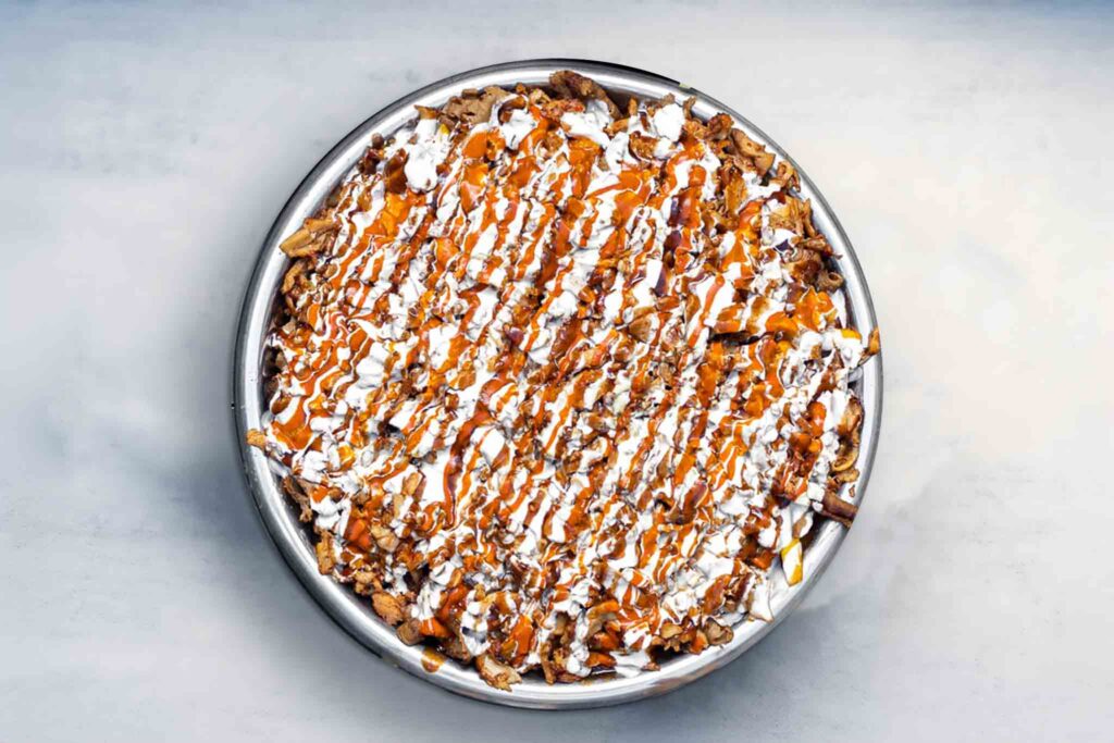 Image of the Glenny Twins Halal Snack Pack, a massive feast with crispy chips, melted cheese, tender meat, and sauce, served for sharing.