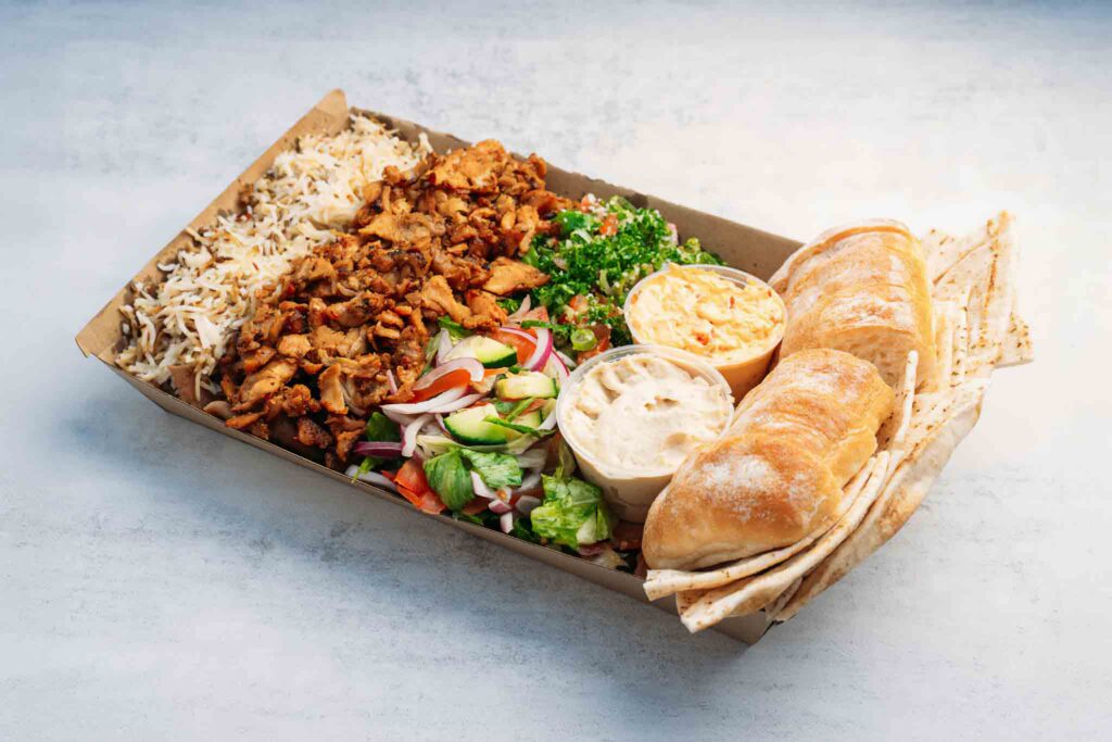 A vibrant Middle Eastern feast featuring meat, tabouli salad, garden salad, and cumin-infused basmati rice, served with Turkish pita bread and two dips.