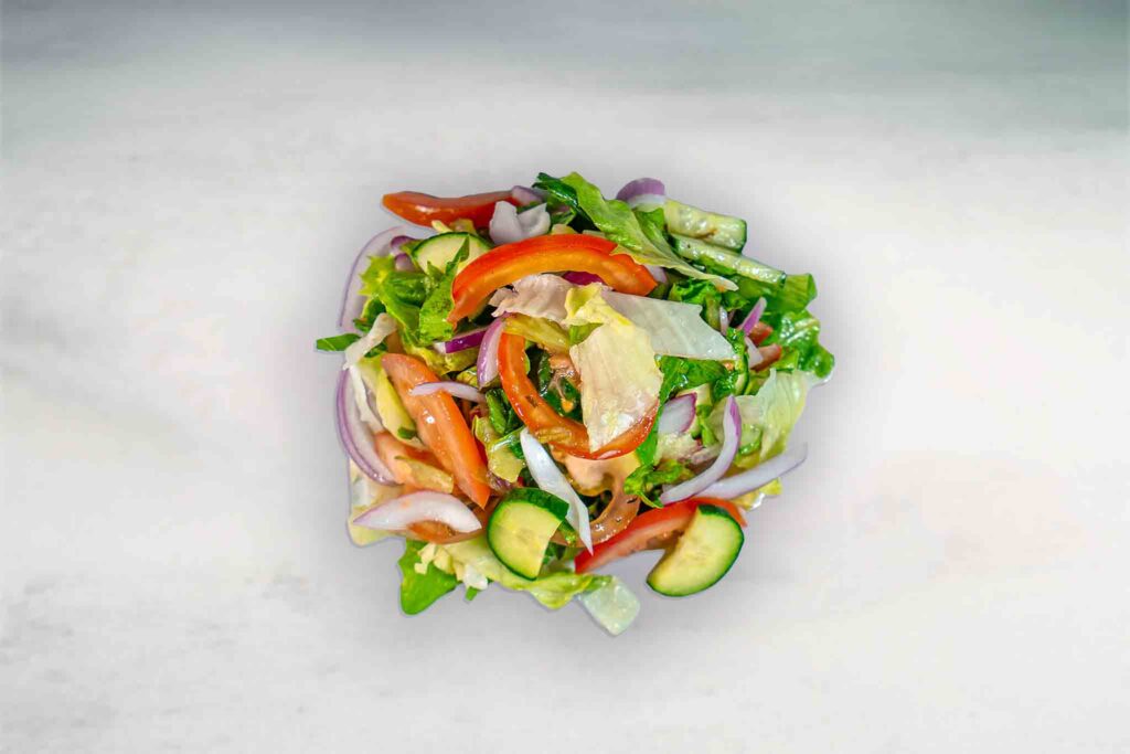 A fresh garden salad with iceberg lettuce, gourmet tomato, red onion, continental cucumber, and a special dressing.
